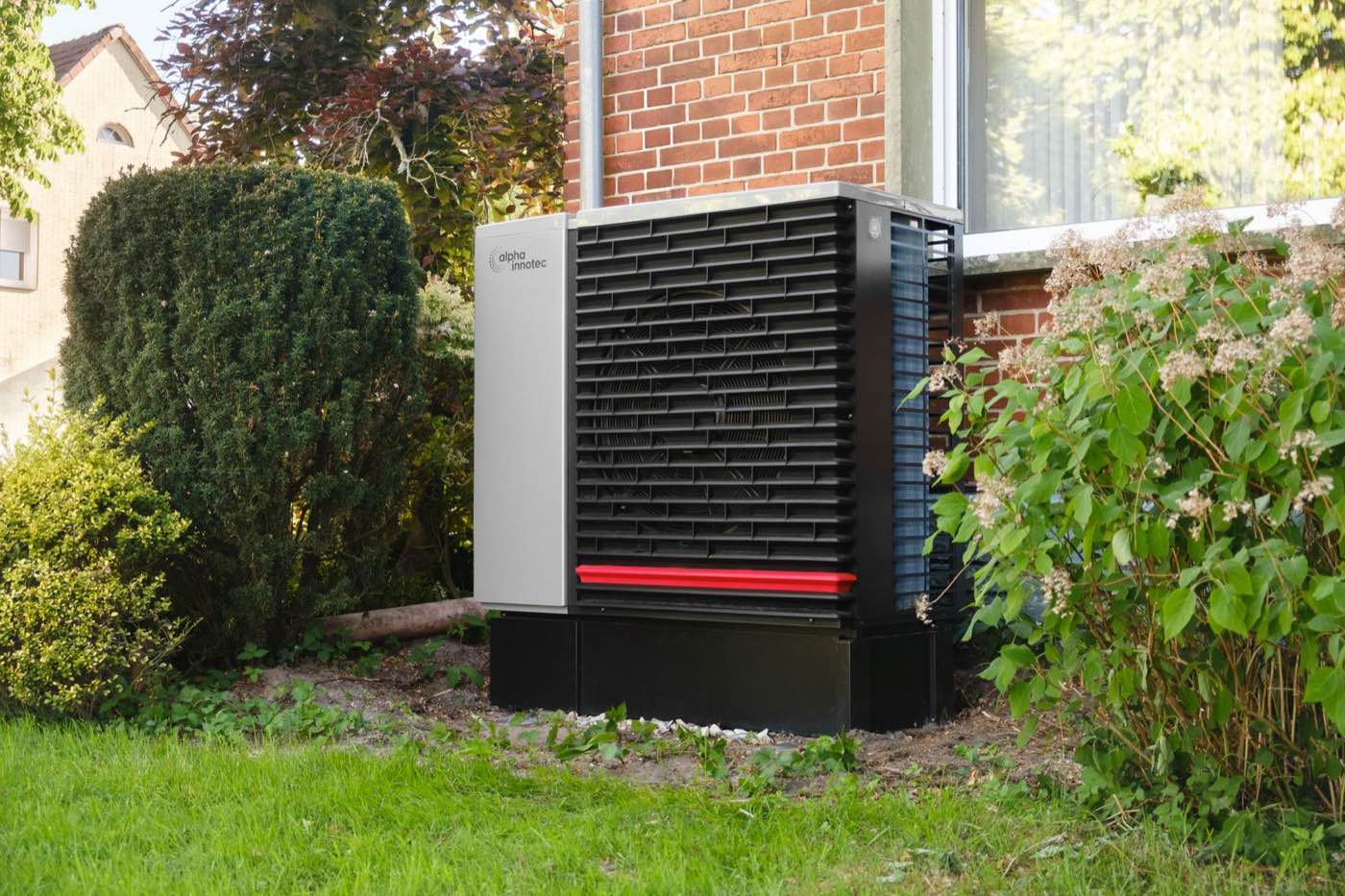 Thermopompe résidentielle installée contre le mur extérieur d'une maison en brique — l'option la plus économique à l'usage